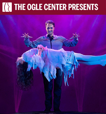 Magician levitates a woman in a ghostly white costume on a spooky stage with purple lighting, fog, skulls, and graveyard scenery.